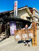 　地震で大きな被害を受けた松波酒造の店舗前でのれんを掲げる若女将の金七聖子さん＝１月、石川県能登町（本人提供）