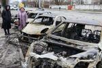 　ウクライナ・キーウで、ロシアの攻撃後、損傷した車両を見つめる女性＝１月（共同）