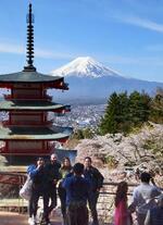 　桜が見頃を迎えた「新倉山浅間公園」で、富士山をバックに記念撮影する外国人観光客ら＝１３日、山梨県富士吉田市