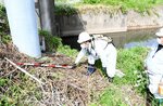 測量用ポールで護岸の亀裂の状態を確認する担当者＝１７日、鳥取市吉成南町１丁目