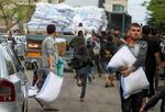 　６日、イスラエル軍がパレスチナ自治区ガザ南部ラファからの退避を要求後、小麦粉の袋をつかむ住民たち（ロイター＝共同）