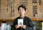 　書籍「声を掬う」を手にする高山智行さん＝仙台市の震災遺構・荒浜小