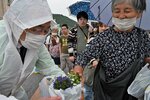  小雨の中を並び、ロベリアの苗を受け取る参加者ら＝２９日、鳥取市の若桜橋 