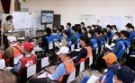 　石川県七尾市のボランティアセンターで、一般のボランティア（手前）とともに活動の説明を受ける県職員ら（奥）。本年度の新規採用職員も研修として参加した＝１７日午前