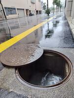 急激な雨水の流入で蓋が内側から自然に開いてしまったとみられるマンホール＝15日午前11時20分、鳥取市富安2丁目
