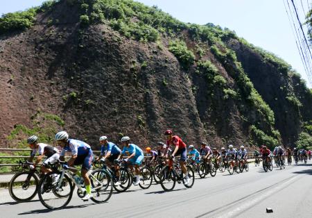 　「ツール・ド・熊野」が開幕し、国の天然記念物「一枚岩」の前を走行する選手たち＝１０日午前、和歌山県古座川町