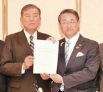 自民党県連会長の石破氏（左）から出馬要請書を受ける平井氏＝昨年１２月２４日、鳥取市内のホテル