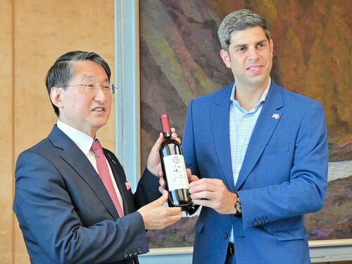 平井知事（左）にジョージアワインを手渡すレジャバ駐日ジョージア大使＝４日、鳥取県庁