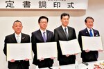 署名した協定書を掲げる磯野社長（左から３人目）ら＝２２日、米子市明治町の米子ワシントンホテルプラザ