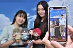 ＡＲでキャラクターと記念撮影するファン＝１日、岩美町浦富