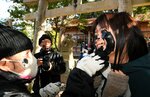 顔に墨を塗られる女性（右）＝７日、松江市美保関町片江の方結神社