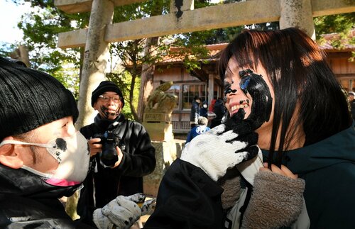 顔に墨を塗られる女性（右）＝７日、松江市美保関町片江の方結神社