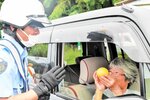 「事故なし」に掛けた梨をドライバーに手渡す参加者＝２０日、香美町香住区下岡の国道１７８号