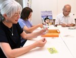 キーホルダーを袋詰めする藤田代表理事（左）ら
