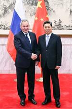 　ロシアのショイグ安全保障会議書記（左）と握手する中国共産党中央政法委員会トップの陳文清書記＝１３日、北京（新華社＝共同）