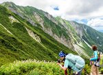 大山北壁をバックに花を撮影する登山者