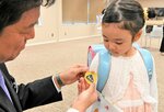 黄色いワッペンを付けてもらう新１年生＝２日、鳥取市役所