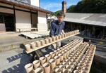 　成形した器を乾燥させるために外に出す黒木昌伸＝２０２４年１１月、大分県日田市（撮影・林昌三）
