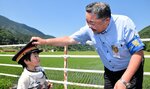 やくもの撮影に来た子どもに制帽をかぶせる和田駅長（右）＝１４日、日野町下榎