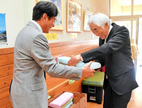岩美南小で卒業生から寄せられた鍵盤ハーモニカを受け取る宮本さん（右）
