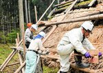穴が開いた部分にカヤを差し込み、木の板で形を整える会員＝１８日、香美町小代区広井の古代体験の森