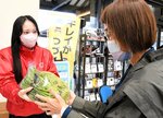 商品を購入した来店者（右）に野菜を手渡す倉吉農業高生