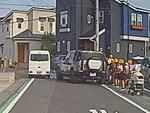 　埼玉県三郷市の市道で、小学生らの脇に止まった車（右）＝１４日（住民提供）