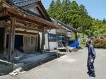 　能登半島地震で全壊した本堂を見つめる徳善寺の住職のり元昌延さん（のりの字は、合の口が正）＝５月、石川県輪島市