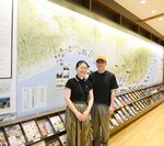 「みちのく潮風トレイル」の地図の前に立つ浜口聡子さんと哲さん夫妻＝宮城県名取市の「名取トレイルセンター」