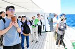 ガイド（中央）の説明を聞きながら、ジオサイトを写真に収める参加者たち＝２８日、香美町沖