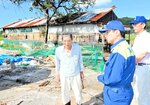 半壊した旧鶏舎の前で金沢さん（左）から被害状況を聞く平井知事（中央）＝１日、伯耆町立岩