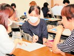 相談しながら案内文書の修正に取り組む事務職員ら