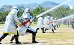 横一列に展開して一斉放水する消防団員＝１４日、香美町香住区香住のしおかぜ香苑