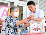 買い物客へ啓発グッズを手渡し被害防止を呼びかける参加者（右）