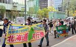 　原発の再稼働反対などを訴える横断幕を手に行進する参加者＝５日午後、札幌市