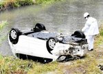 袋川沿いに転落した乗用車＝１４日午前９時５５分、鳥取市栄町の袋川土手