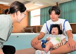 赤ちゃんと触れ合い、母親から子育てについて話を聞く生徒（右）