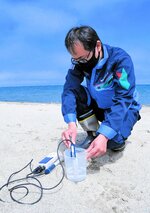 海水浴場の海水をくみ取り、水質を調査する業者＝１５日、鳥取市賀露町