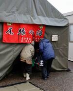 　支援の最終日を迎えた自衛隊の入浴施設ののれんをくぐる利用者＝１５日午後、石川県珠洲市大谷町