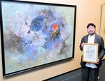 受賞作品「群泳」の前で賞状を掲げる松岡さん