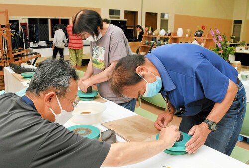 小原さん（左）から助言をもらいながら手ろくろ体験をする参加者＝１３日、倉吉市上井町１丁目の日本海新聞中部本社ホール
