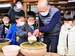 坂本さん（左から５人目）と一緒に釉薬掛けに挑戦する児童＝７日、鳥取市河原町中井の因州・中井窯