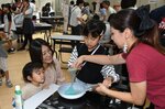 店員の手ほどきを受けながらお菓子作りに挑戦する親子＝２３日、倉吉市のエースパック未来中心