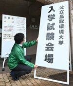  会場前に看板を立てる職員＝２２日、鳥取市若葉台北１丁目の鳥取環境大 