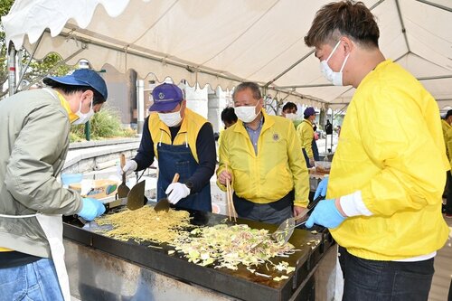 屋台の実演販売で焼きそばを作るクラブ会員