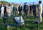 最新の農薬散布ドローンについて説明を受ける参加者ら
