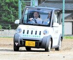 グラウンドを走行し乗り心地を確認するテストドライバー（左）