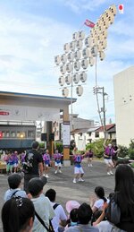 屋根の前で万灯を披露する子どもたち＝２０日、米子市道笑町１丁目のパティオ広場