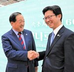 職員の相互派遣を再開する方針を共有し、握手する伊木市長（右）と李市長＝７日、韓国・束草市