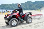 ビーチクリーナーでごみを回収する参加者＝１６日、岩美町の東浜海水浴場
